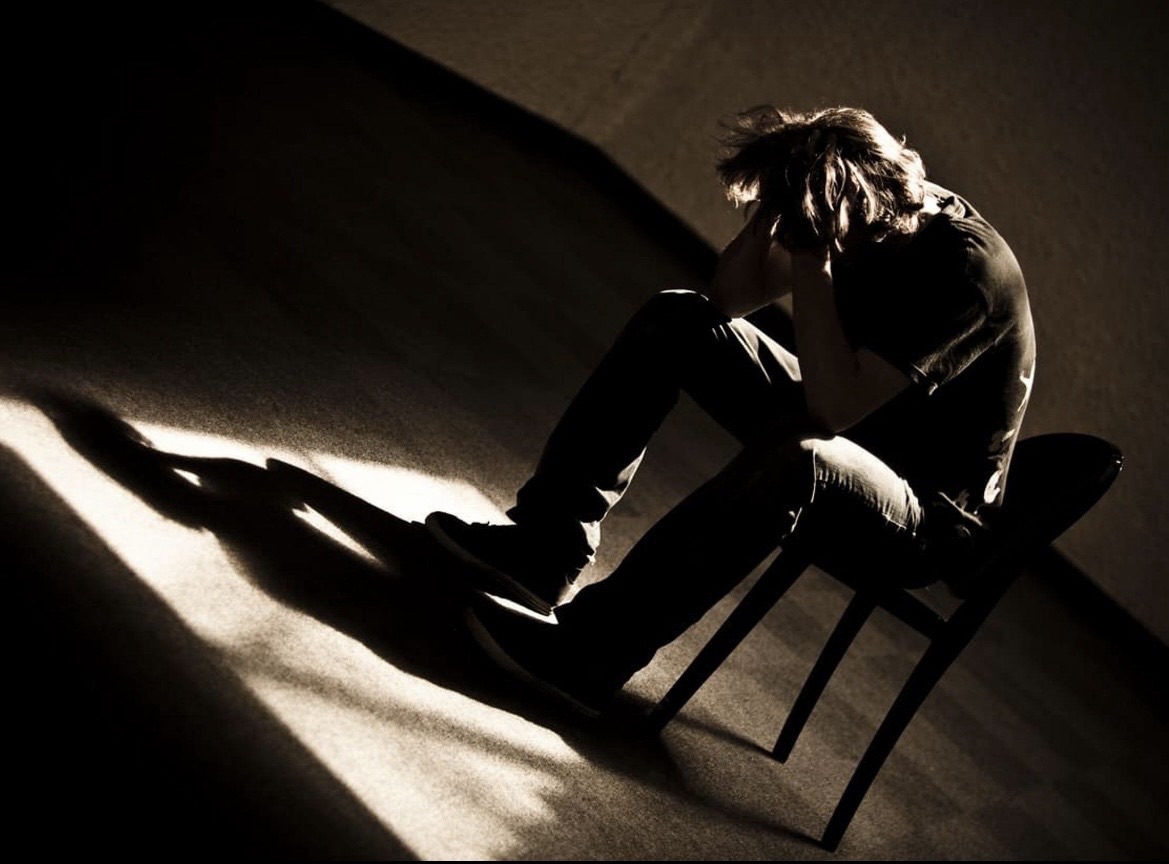 person sitting in darkness struggling with addiction depression and recovery journey emotional pain and healing process